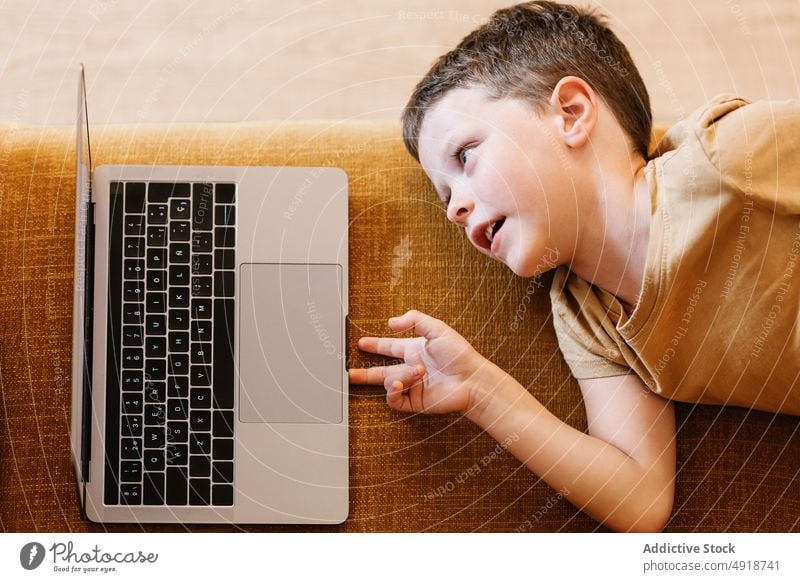 Junge auf einem Sofa liegend, der den Laptop benutzt Kind Computer Kaukasier Technik & Technologie männlich im Innenbereich heimwärts Kindheit wenig Spiel