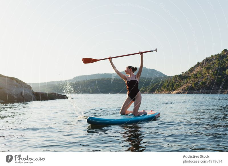 Frau in Badekleidung schwimmt auf Paddleboard Paddelbrett sportlich Surfer Hobby See Wasser Reihe üben Schwimmer Baum Küste Gerät Zusatzplatine Abenteuer