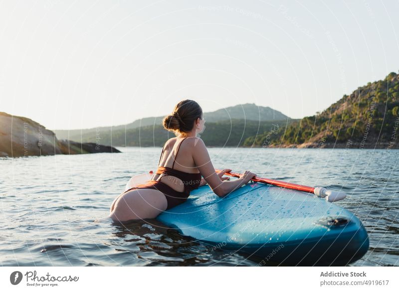 Frau auf Paddleboard im See liegend Paddelbrett Freizeit Hobby Wasser ruhen Natur Wohlbefinden Badebekleidung Sommer Zusatzplatine schlanke Ufer Schwimmer