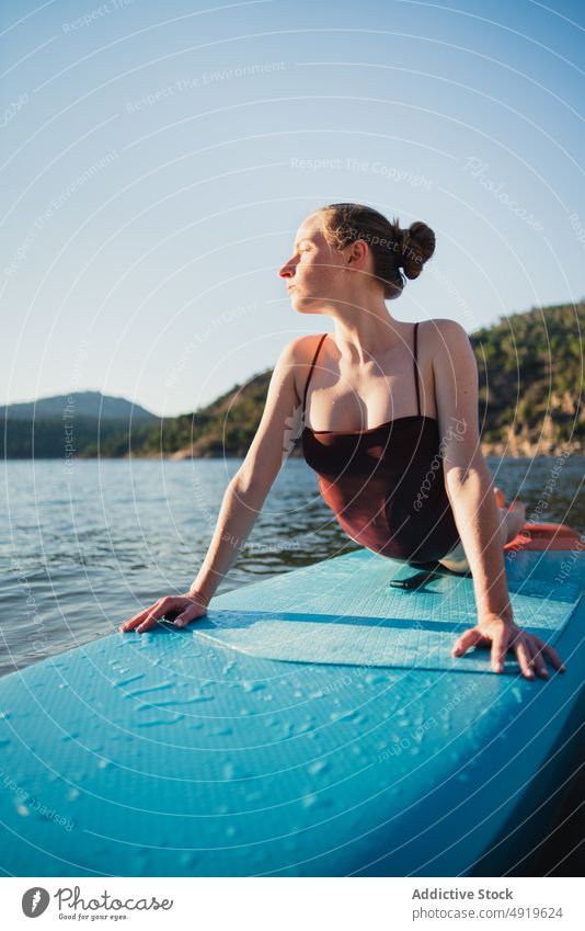 Frau auf Paddleboard im See liegend Paddelbrett Freizeit Hobby Wasser ruhen Natur Wohlbefinden Badebekleidung Sommer Zusatzplatine schlanke Ufer Schwimmer