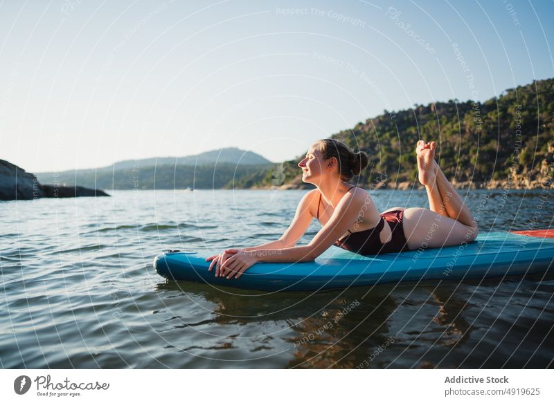 Frau auf Paddleboard im See liegend Paddelbrett Freizeit Hobby Wasser ruhen Natur Wohlbefinden Badebekleidung Sommer Zusatzplatine schlanke Ufer Schwimmer