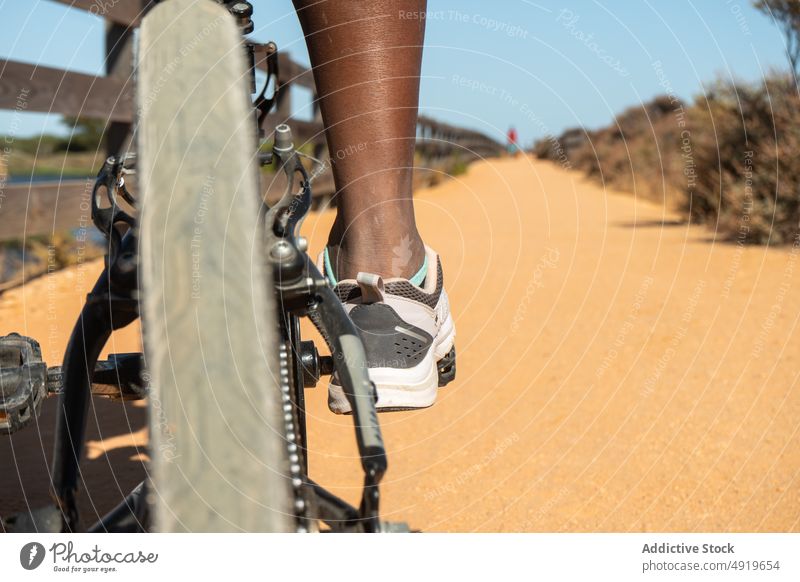 Anonyme schwarze Frau auf einem Fahrrad Rad Bein vereinzelt Transport Sport Zyklus Verkehr Weg Radfahren Objekt Sand Aktivität Symbol Mitfahrgelegenheit Rennen