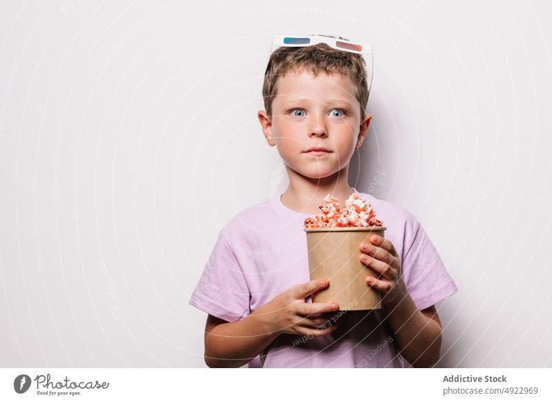 Staunender Junge mit 3D-Brille und Popcorn Kind 3d Popkorn Snack Vergnügen Erstaunen Film Schock Leckerbissen wow Licht Eimer starren erstaunt verblüfft Hobby
