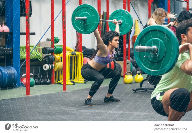 Frau übt Gewichtheben in der Turnhalle Heben Curl-Hantel Greifen Arme hoch Cross-Training Fitnessstudio Überwindung Überkopfhocke Sportlerin selbstbewusst Zug