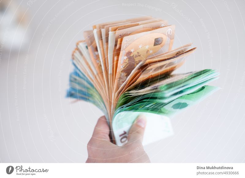 Hand hält ein Bündel Euro-Banknoten in Großaufnahme. Inflation in der Europäischen Union Konzept. Geld auf weißer Oberfläche isoliert. Stapel von einhundert, fünfzig und zwanzig Euro-Noten. Tausende von Euro-Barzahlungen Konzept. Deposit Geld, Darlehen, Hypothek Konzepte.