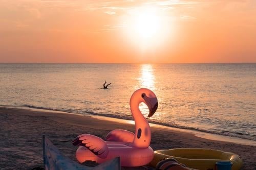 Spaß am Strand. Aufblasbare Schwimmen Rad Spielzeug in Form von rosa Flamingo auf Sonnenuntergang Strand. Kind spielen im Wasser.  Konzept der Sommerferien am Meer. Glückliche Kindheit magische Momente.