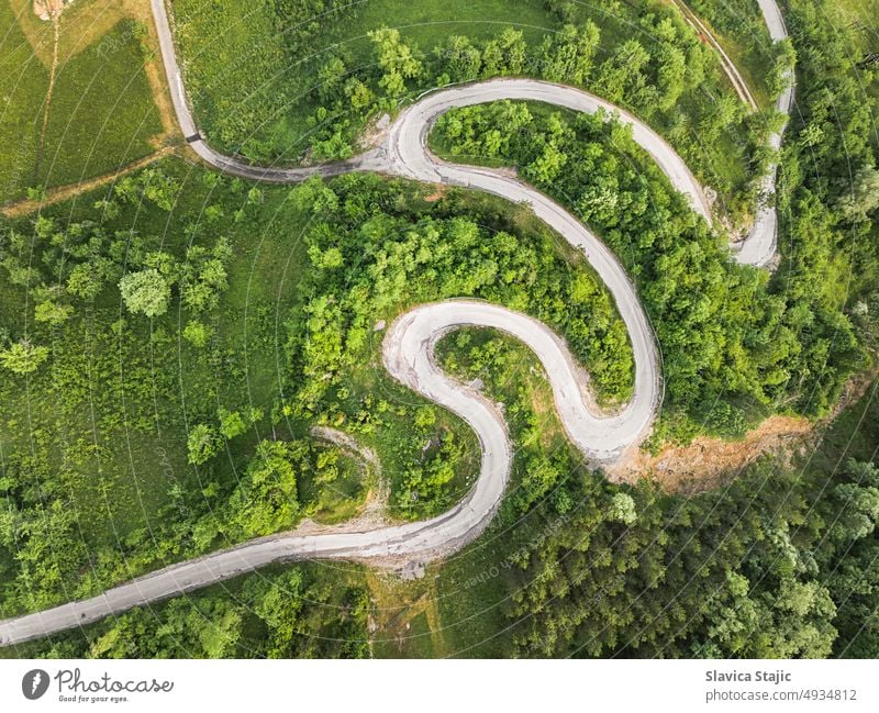 Drohnenansicht einer schönen Serpentinenstraße, die durch eine Berglandschaft im Sommer führt.  Luftbildaufnahme einer Straße, aufgenommen mit einer Drohne.  Beschädigte Straßenoberfläche