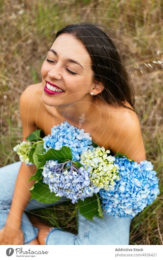 Glückliche, verführerische Dame mit einem Strauß zarter Hortensienblüten im Park Frau Blume Lächeln oben ohne Wiese Deckbrust feminin positiv sanft Feld