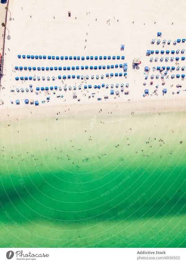 Luftaufnahme von Sonnenliegen und Sonnenschirmen am breiten Sandstrand Meer Strand Meeresufer Resort Sonnenbank Regenschirm Küstenlinie Meereslandschaft