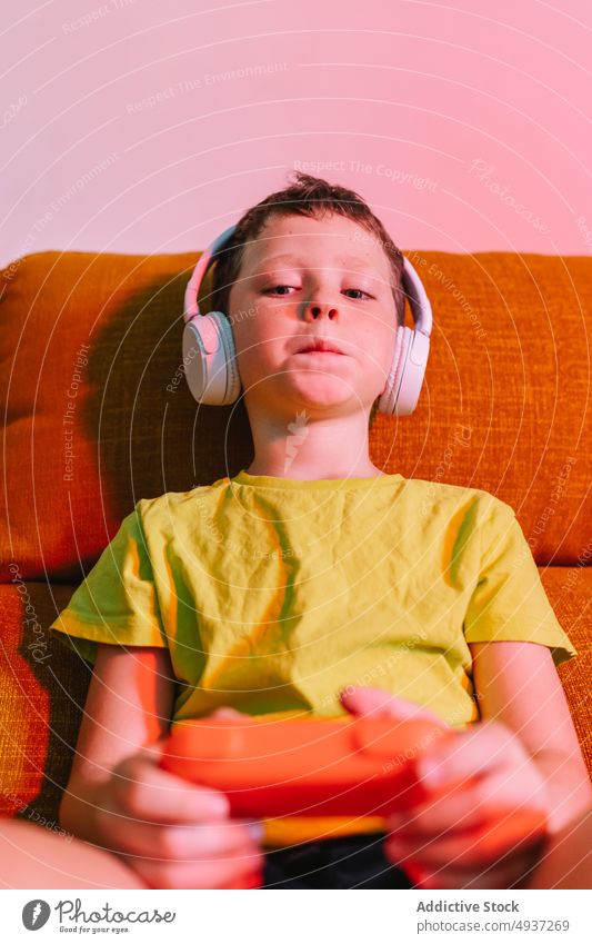 Konzentrierter Junge beim Videospiel Kind spielen unterhalten konzentriert Vergnügen Zeitvertreib fokussiert Wohnzimmer Kopfhörer genießen Freizeit Abend Liege