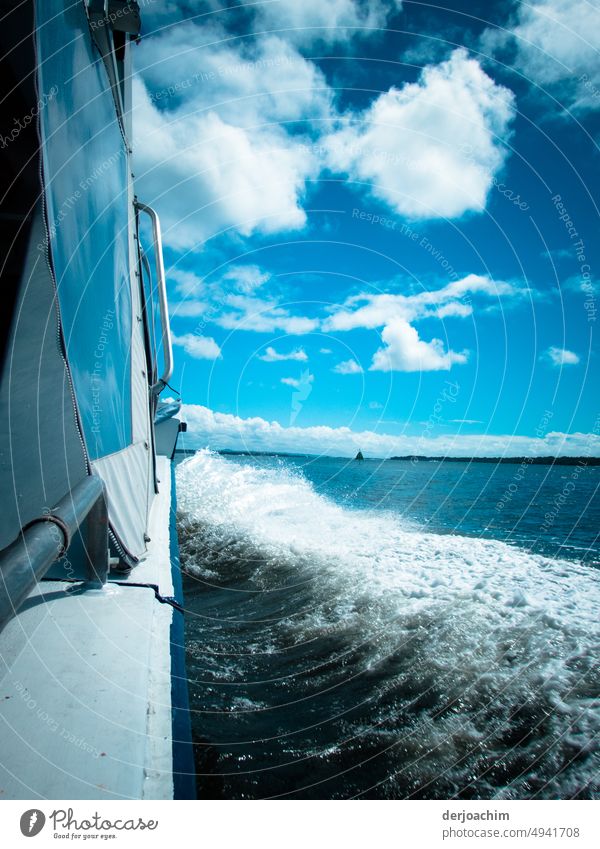 Das Boot fährt mit schneller Fahrt auf der Steuerbord Seite durch die Wellen. Im Hintergrund am Horizont ist Land in Sicht. Bootsfahrt Wasser Schifffahrt