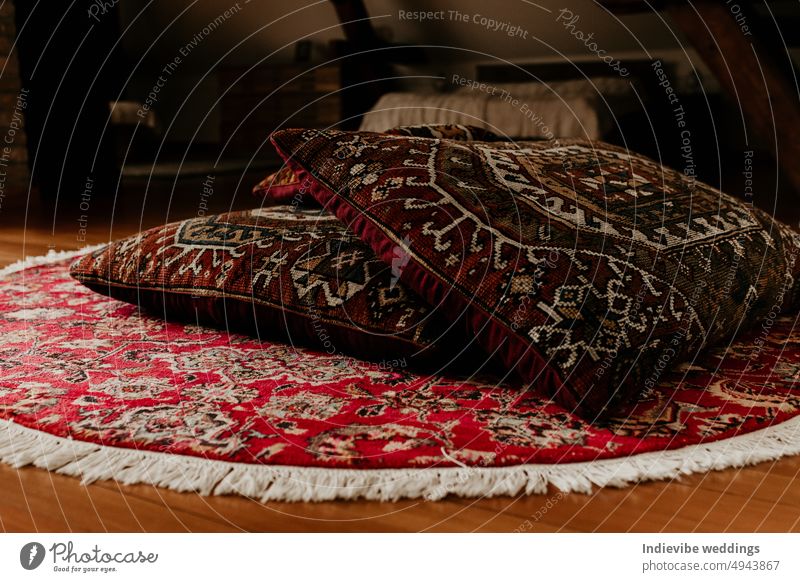 Zwei rote persische Bettkissen auf einem runden handgestrickten Teppich auf dem Boden. Home Dekoration Detail, Kopie Raum. Bunte Teppich und Textil. Antiquität