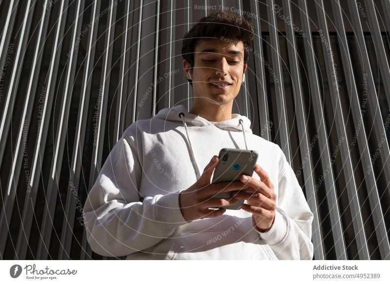 Lächelnder Mann mit Smartphone in der Stadt Nachricht soziale Netzwerke jung Großstadt Surfen Browsen urban Internet männlich benutzend online Glück Straße