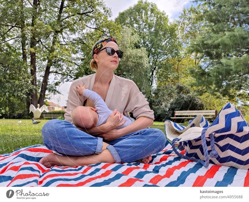 Moderne trendige Mutter stillt sein Baby Junge Kind im Freien in öffentlichen Stadtpark Mama Stillen Mutterschaft Kindheit Frau Lifestyle Familie Brust Glück