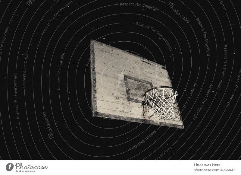 Ein Bild von einem rustikalen Basketballkorb. Mit einem Sternenhimmel als Hintergrund. Eine Sommernacht und ein kreatives Bild eines alten Metallkorbs. Verlassene Sportarten.