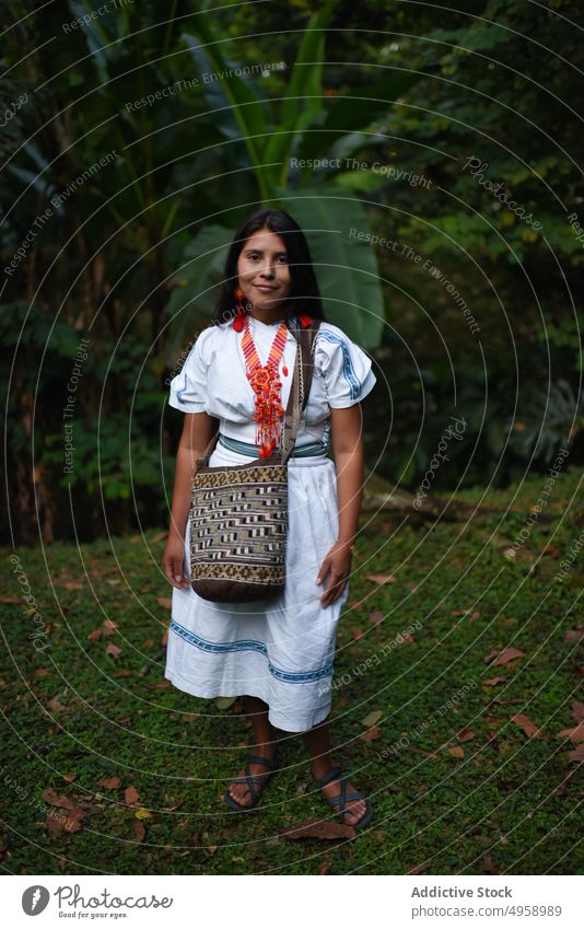 Lächelnde junge einheimische Arhuaco-Frau im Wald Porträt Kolumbien beschaulich 20s Natur Lateinamerika traditionell Kleidung Halskette Tasche handgefertigt