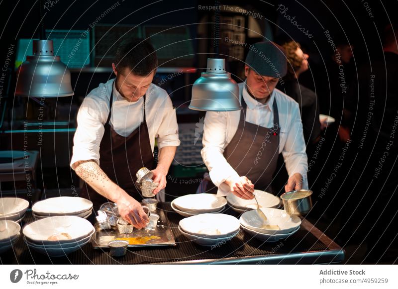 Köche servieren Essen in der Restaurantküche kocht Servieren Mahlzeit Lebensmittel Küche Speise Küchenchef Mann professionell Teller Uniform männlich Menschen