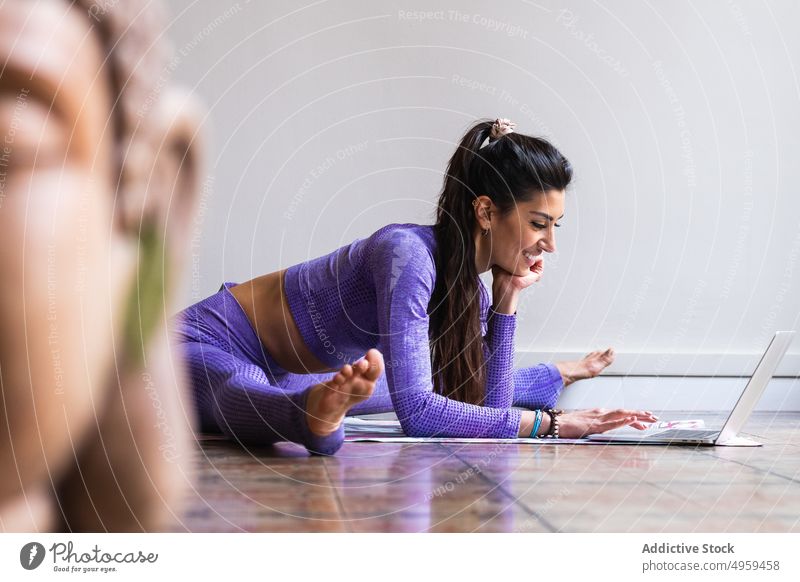 Flexible ethnische Frau mit Laptop beim Yoga-Training zu Hause benutzend Tutorial online positiv beweglich Achtsamkeit digital Wohlbefinden Internet jung