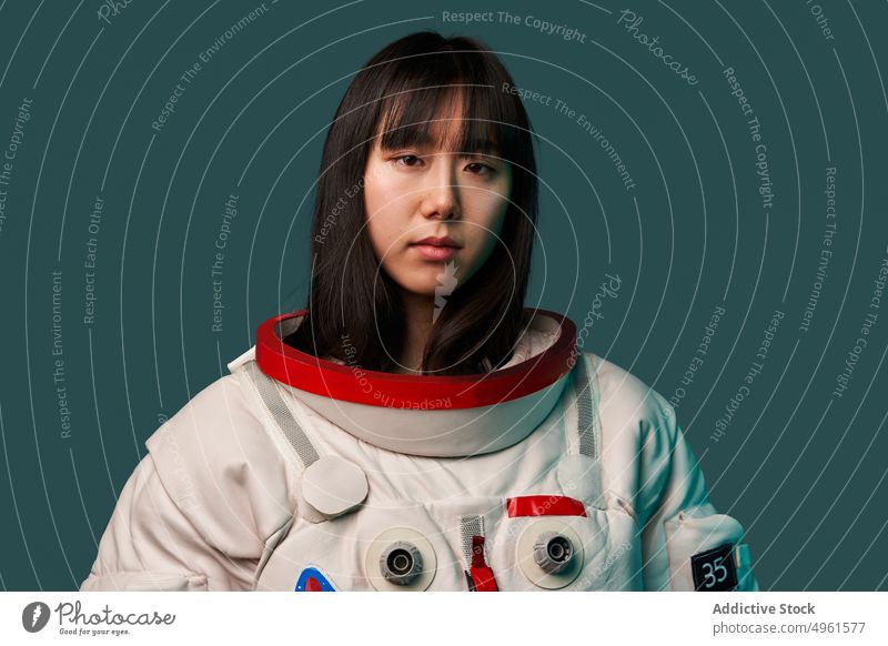 Ruhiger asiatischer Kosmonaut schaut in die Kamera Frau bereit Missionsstation Windstille ernst Raumanzug futuristisch modern jung Chinesisch Japanisch