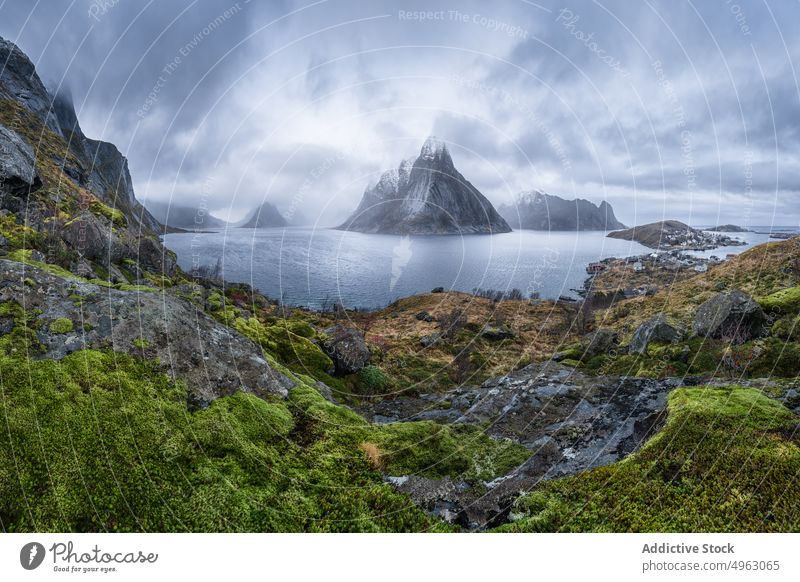 Kleine Siedlung am Meer in der Nähe von felsigen Bergen gegen bedeckten Himmel Berge u. Gebirge MEER Natur Winter Häuser Fjord Dorf malerisch Kamm Landschaft