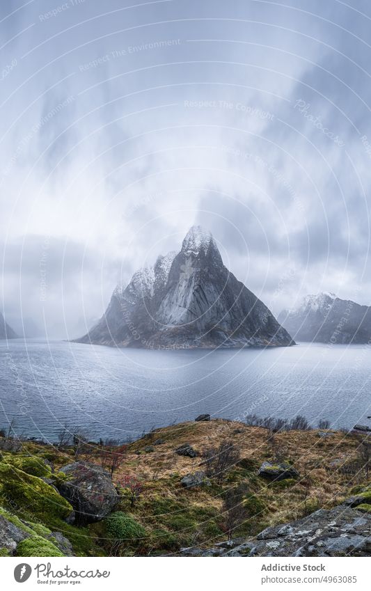 Küste in der Nähe von felsigen Bergen gegen bedeckten Himmel Berge u. Gebirge MEER Natur Winter Fjord malerisch Kamm Landschaft Meeresufer Schnee