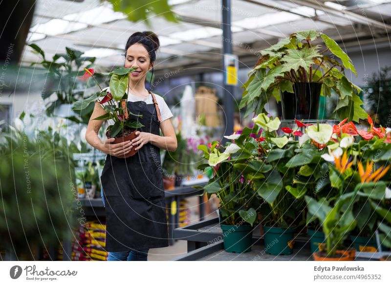 Aufnahme einer jungen Frau bei der Arbeit mit Pflanzen in einem Gartencenter Gärtnerei Lächeln Positivität Natur Gartenarbeit kultivieren Wachstum Hobby Frische