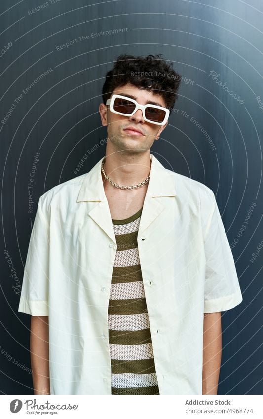 Stylischer junger Mann mit Sonnenbrille Stil Mode trendy krause Haare Streetstyle Porträt selbstbewusst Outfit männlich ernst Vorschein Persönlichkeit