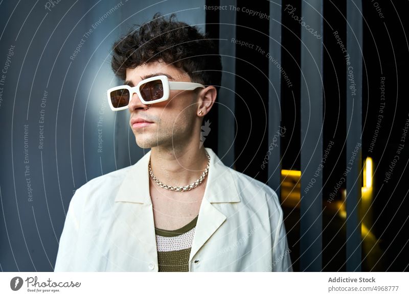 Stylischer junger Mann mit Sonnenbrille Stil Mode trendy krause Haare Streetstyle Porträt selbstbewusst Outfit männlich ernst Vorschein Persönlichkeit