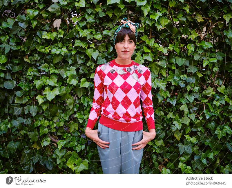 Stilvolle Frau in Retrokleidung im Park altehrwürdig Kopftuch retro Mode Pflanze Lächeln froh Hecke grün heiter Glück stehen Freude Sommer trendy positiv Dame