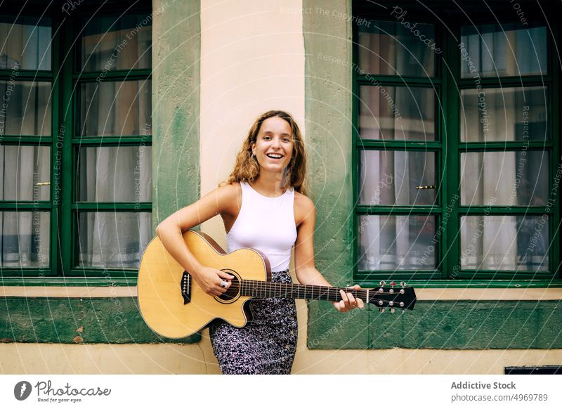 Lockige Frau spielt Gitarre und lehnt sich an die Wand Musik Spielen romantisch jung spielen Instrument heiter Musical Spaß Urlaub Mode Feiertag lässig Sommer