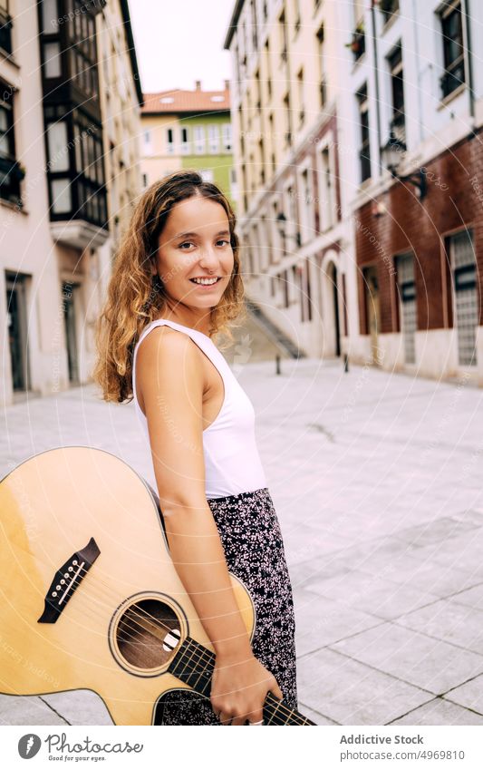 Charmante lockige Frau mit einer Gitarre und Blick in die Kamera Musik romantisch jung spielen Instrument heiter Musical Spaß Urlaub Mode Feiertag lässig Sommer