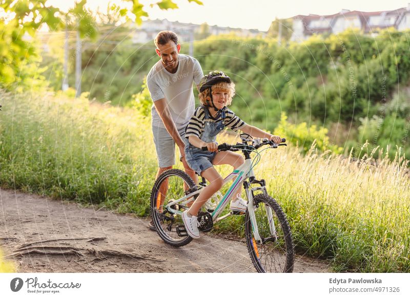 Vater bringt seinem Sohn das Fahrradfahren bei Tag Gesunder Lebensstil aktiver Lebensstil im Freien Spaß Freude Radfahren Aktivität Radfahrer genießend