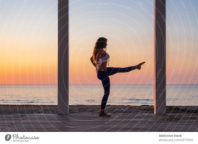 Flexible Frau macht Yoga am Meer bei Sonnenaufgang Pose Seeküste Terrasse ruhig Sportbekleidung üben MEER hölzern anjaneyasana Gelassenheit Gesundheit Harmonie