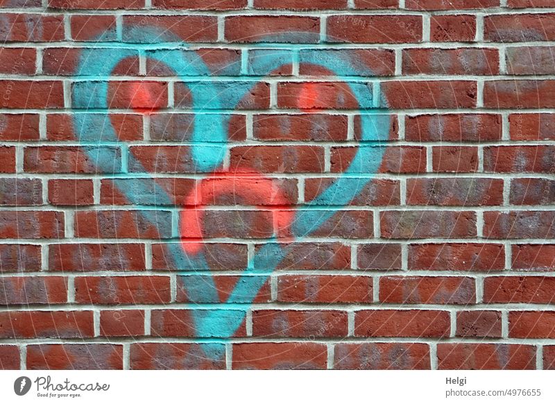 Liebeskummer? - ein türkisfarbenes gesprühtes Herz mit traurigem Gesicht auf einer roten Backsteinwand Farbe farbig Wand Mauer Klinker Klinkerwand Graffiti