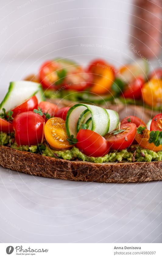 Toast mit Kirschtomaten und Avocado Zuprosten gestampft cucucmber Avocado-Toast Brot Mikro-Grün Mittagessen Frühstück frisch Lebensmittel Vegetarier Gesundheit