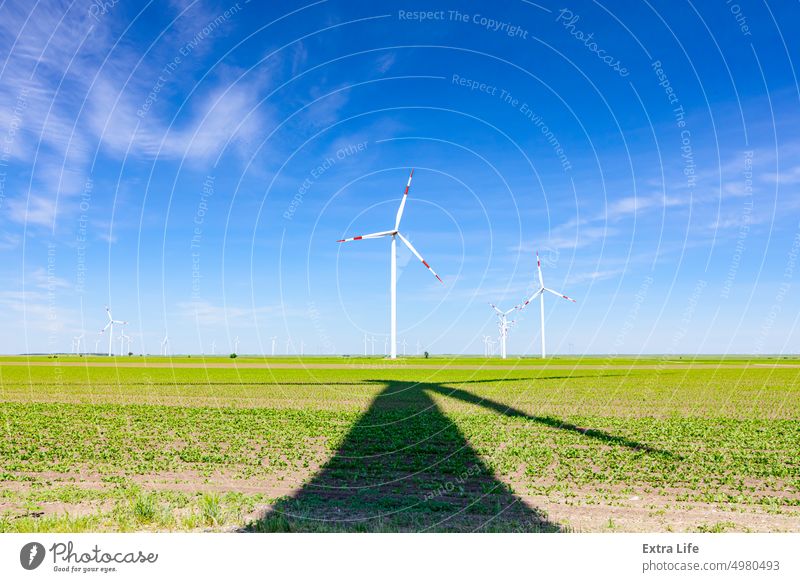 Langer Schatten unter dem Windrad: große Windkraftanlagen drehen sich und erzeugen saubere, grüne, erneuerbare Energie alternativ unten darunter Sauberkeit