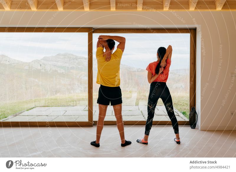 Schlanke Frau und Mann stehen im Raum und dehnen sich Dame Typ Schiffsplanken Sport Sportbekleidung sportlich schlank aktiv Fenster Aktivität gymnastisch