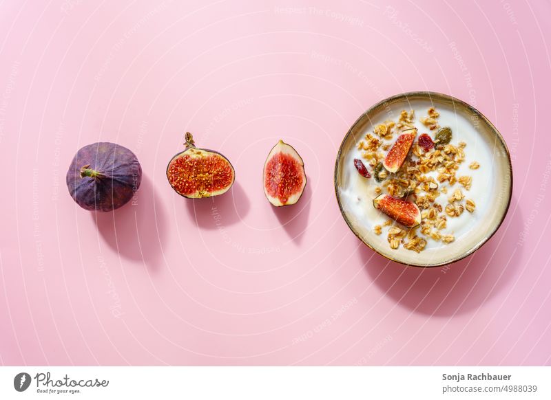 Eine Schüssel mit Müsli, Joghurt und Feigen auf einem rosa Hintergrund. Frühstück. süß Ernährung Haferflocken Porridge Diät Gesundheit Frucht Lebensmittel