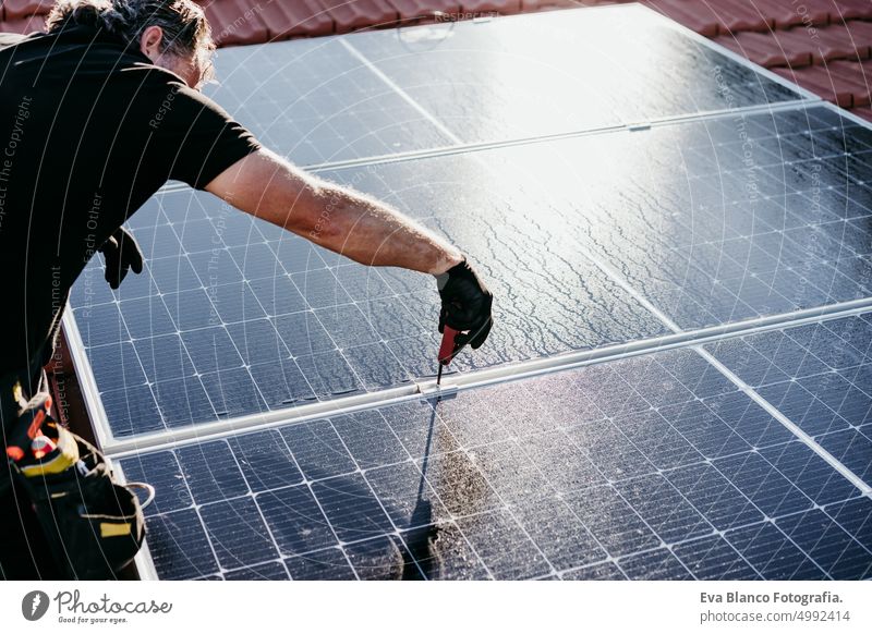 reifen Techniker Mann Montage von Sonnenkollektoren auf Hausdach für den Eigenverbrauch Energie. Erneuerbare Energien Konzept Ökostrom Dach Photovoltaik