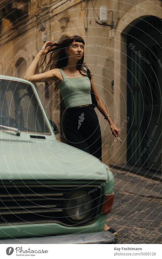 Brünette Frau mit türkisem Hemd steht neben einem türkisfarbenen Auto attraktiv Schönheit brünett brünettes Haar PKW Kaukasier filmisch Großstadt Stadtleben