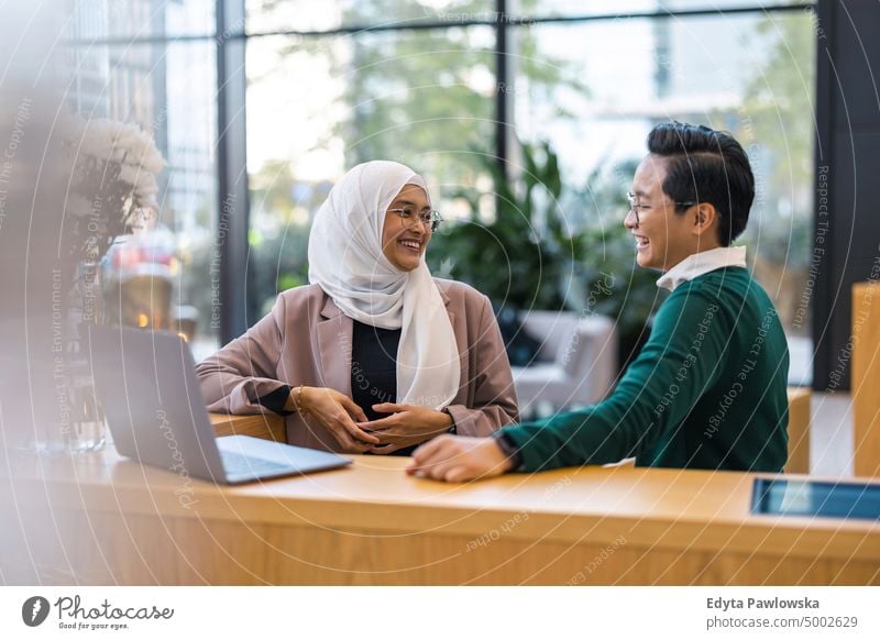 Junges Geschäftspaar benutzt Laptop im Büro multirassische Gruppe Team Vielfalt Teamwork muslimisch multiethnisch Business Menschengruppe echte Menschen jung