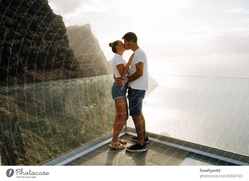 Junges Paar auf einem Aussichtspunkt vor vulkanischen Klippen und dem Meer Liebe Flitterwochen jung Sonnenuntergang Kaukasier Textfreiraum Steine