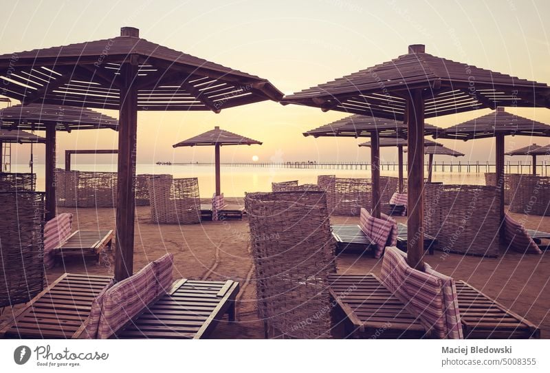 Strand mit Liegestühlen, Sonnenschirmen und Windschutzscheiben bei Sonnenaufgang, farblich getönt, Ägypten. Urlaub friedlich Natur MEER Sommer Sonnenuntergang