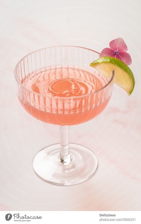 Ein rosafarbenes Cocktailgetränk mit einem Spritztropfen im Glas trinken platschen Kalk Blume Getränke Mocktail geschmackvoll Bar süß Alkohol dienen