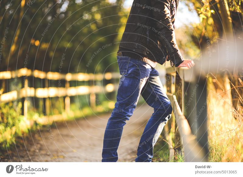 anonymer Mann steht in der Natur gestützt an einem Geländer beobachten ruhe genießen stille cool lederjacke Mode Erholung