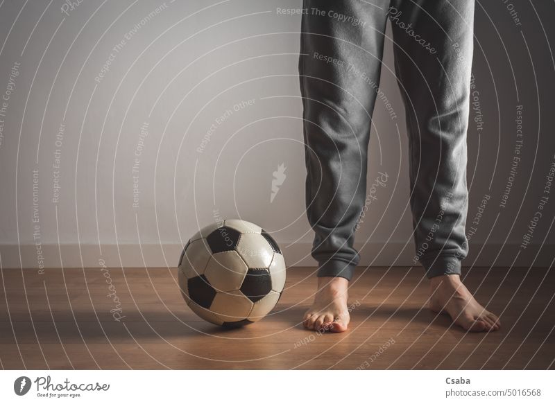 Beine eines Mannes, der neben einem Fußball steht Stehen Raum im Innenbereich Barfuß männlich Ball unkenntlich Erwachsener Person Sport weiß Wand Menschen aktiv