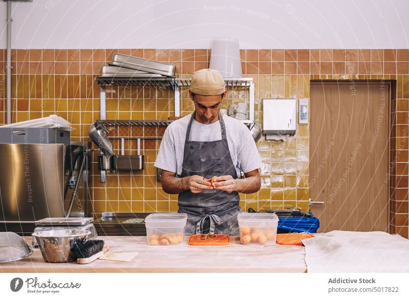 Männlicher Koch beim Schälen von Nektarinen in einer Bäckerei sich[Akk] schälen Frucht Mann frisch Prozess männlich Schürze vorbereiten Tisch Küche Lebensmittel