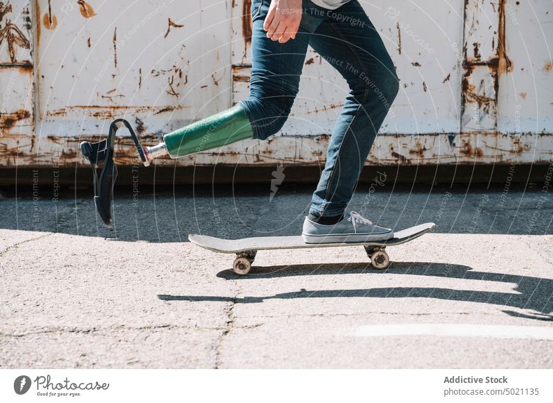 Mann mit Beinprothese fährt Skateboard Mitfahrgelegenheit künstlich Tatkraft Motivation dynamisch Wand Straße Amputierte Großstadt Außenseite jung Beton Energie