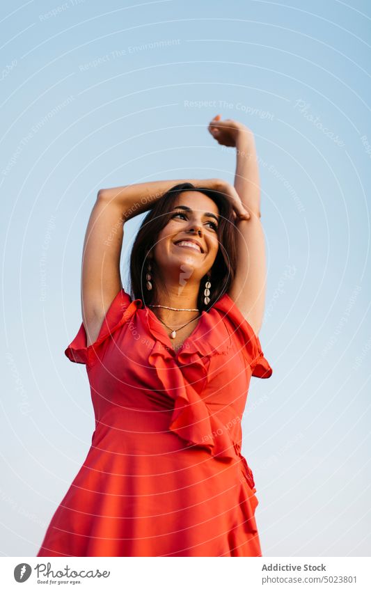 Fröhliche Frau rotes Kleid gegen blauen Himmel Freiheit Glück Stil Blauer Himmel wolkenlos Lächeln Zahnfarbenes Lächeln Outfit Halskette Inhalt Schwarzes Haar