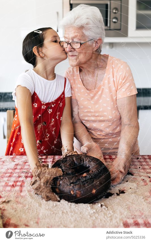 Enkelin küsst Großmutter beim Kochen in der Küche Oma Kuss kulinarisch Rezept vorbereiten Teigwaren Hilfsbereitschaft Umarmen Frau Liebe Mädchen Zeit verbringen